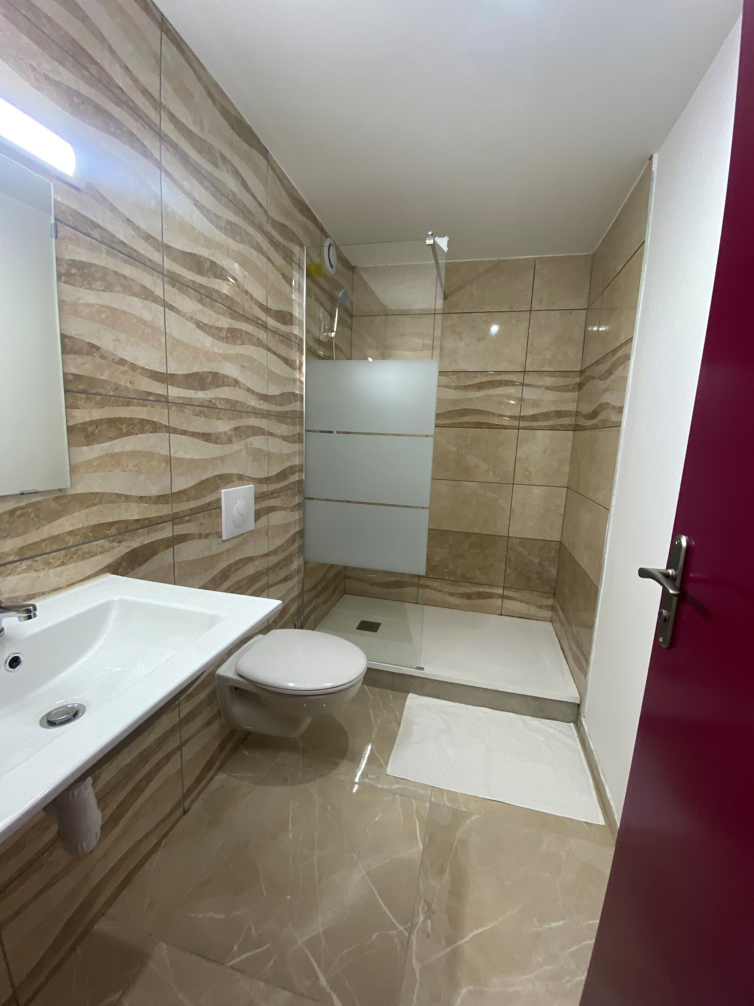Ein modernes Badezimmer mit einem weißen Waschbecken, einer Toilette und einer Duschkabine.