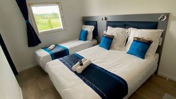 Habitación de hotel con una cama grande, una cama más pequeña y una ventana con cortinas.