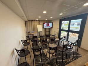Ein Konferenzraum mit einer Tafel, einem Laptop auf einem Tisch und einem Fernseher, der ein Logo zeigt.