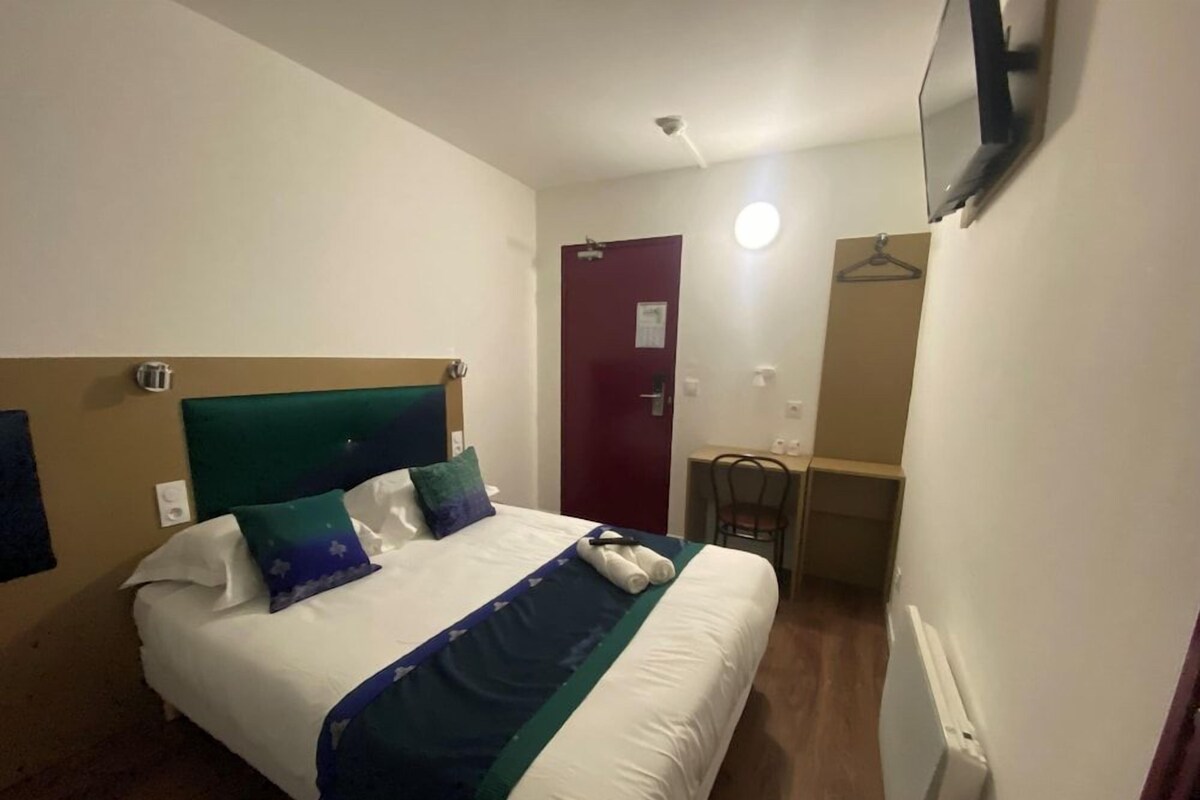 Une chambre d’hôtel avec un lit, un bureau et une chaise.