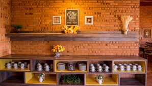 Decoració amb motius de cafè, una paret de maó, una prestatgeria de fusta que exhibeix conjuntes de te i un cartell que diu 'The Coffee Break'.