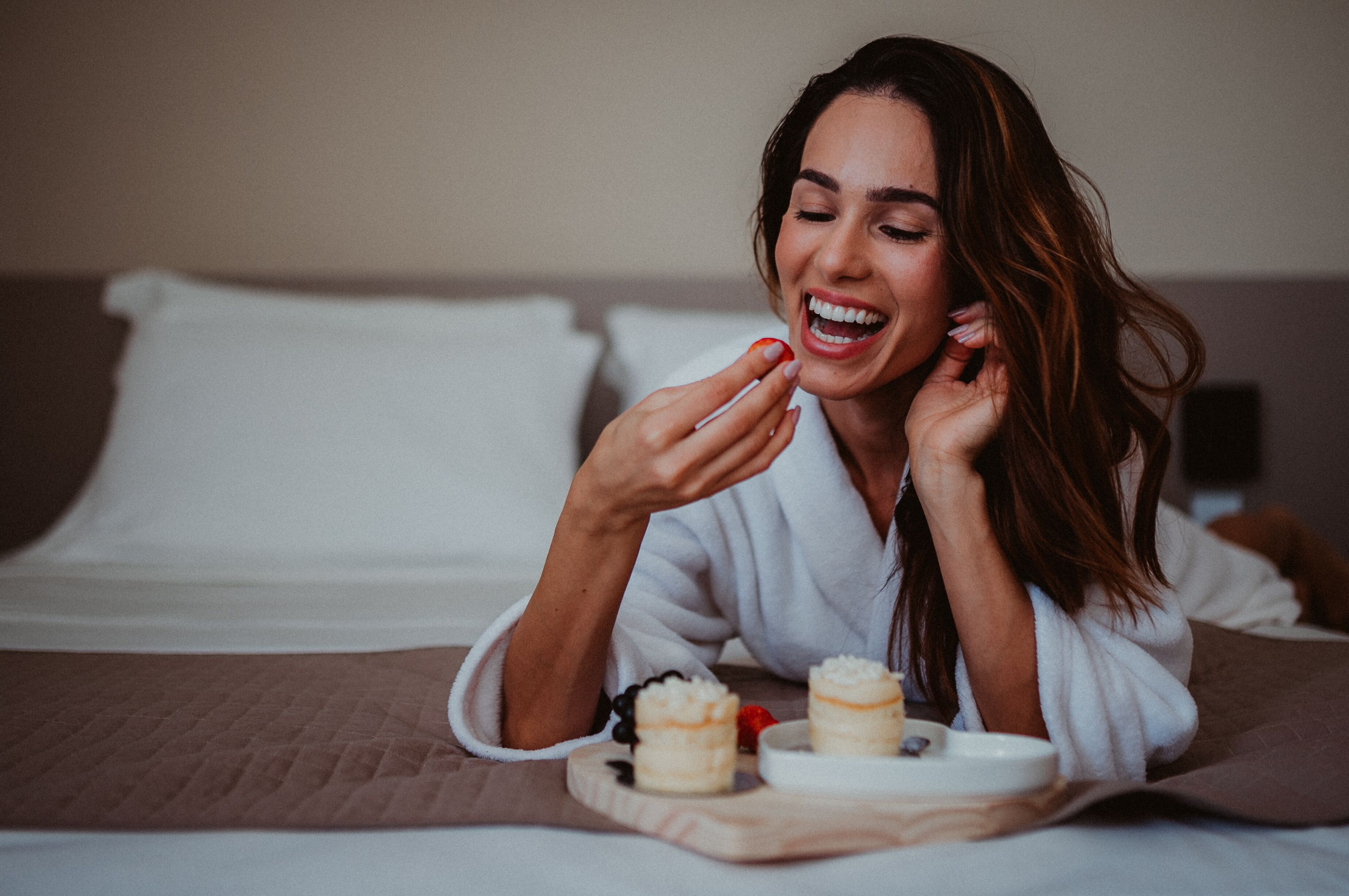 Uma pessoa deitada em uma cama, com um prato de comida e uma xícara.