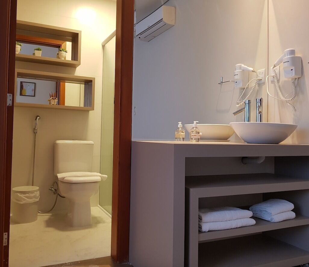 A bathroom with a toilet, a sink with a large basin, a mirror, and a towel rack.