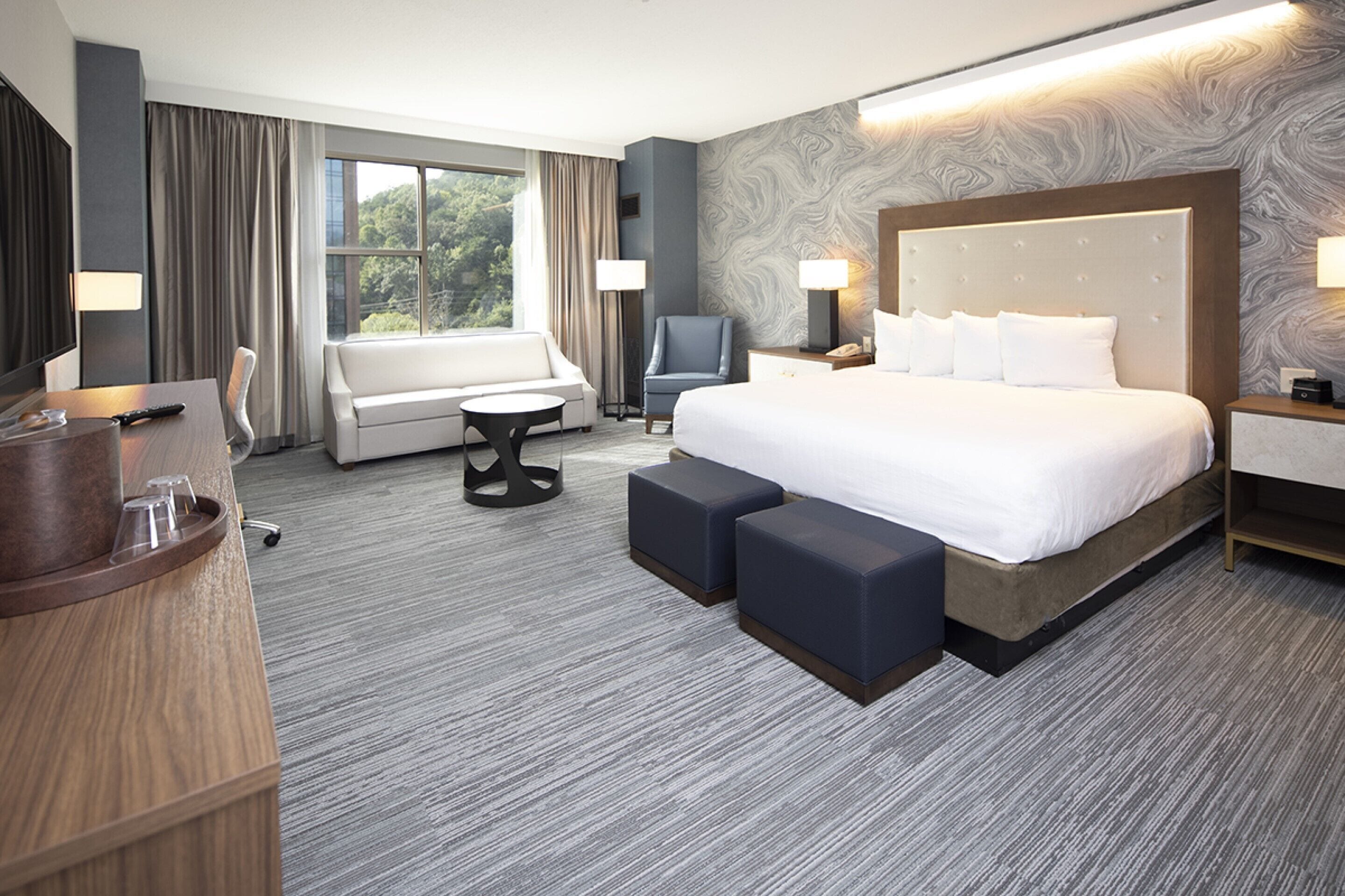 A hotel room with a large bed, a sofa, a desk, and a chair.