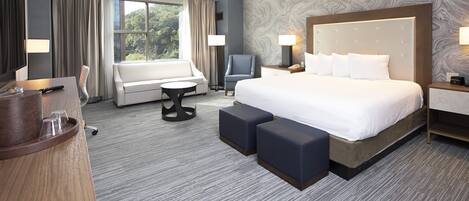 A hotel room with a large bed, a sofa, a desk, and a chair.