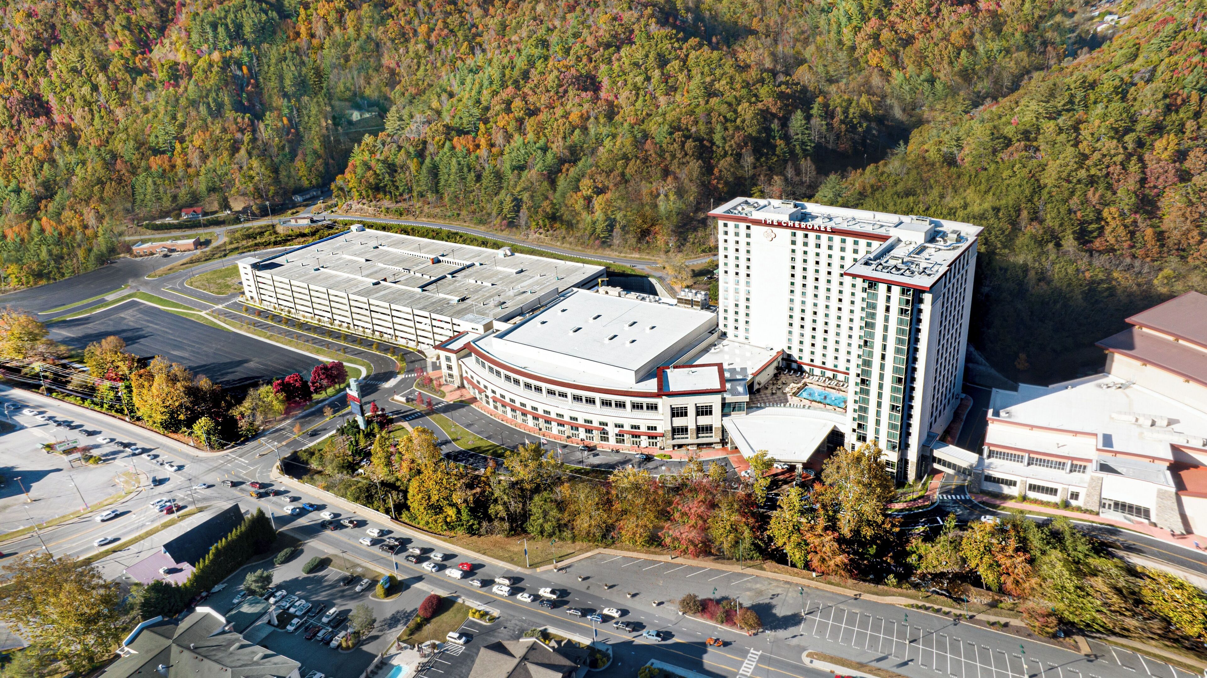 A multi-story building with a flat roof, surrounded by parking areas and trees.