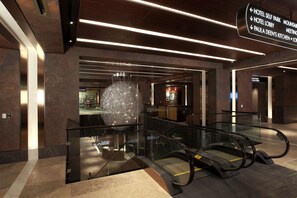 An indoor area with an escalator, a hanging decorative light fixture, and a directional sign indicating hotel self park, lobby, and kitchen locations. - Harrah's Cherokee Casino Resort - A Caesars Rewards Destination (Cherokee)