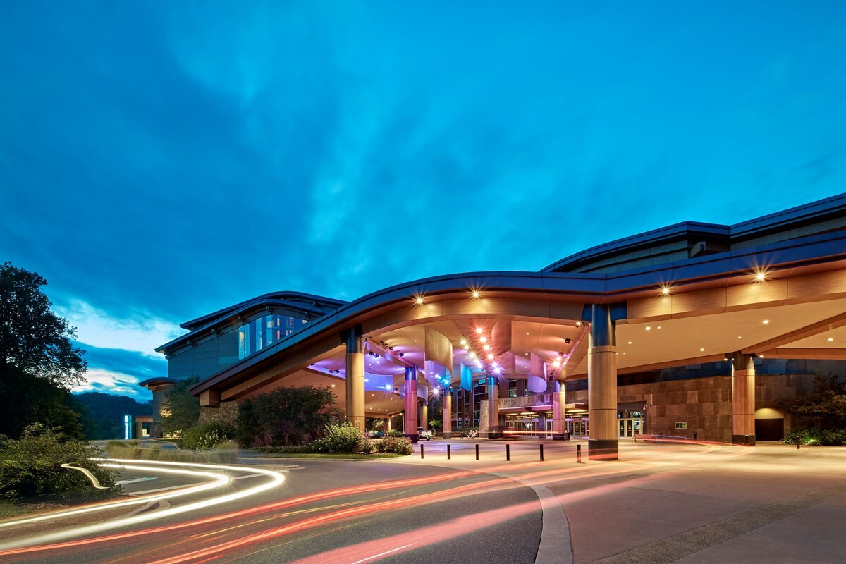 A modern hotel with a curved roof structure, large glass windows, and a well-lit entrance area.