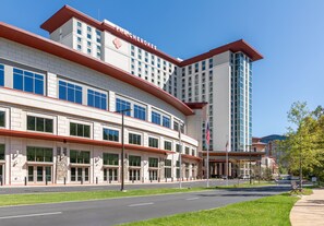 A large hotel with a prominent 'The Cherokee' sign, featuring a modern architectural design with a curved facade and multiple windows. - Harrah's Cherokee Casino Resort - A Caesars Rewards Destination (Cherokee)