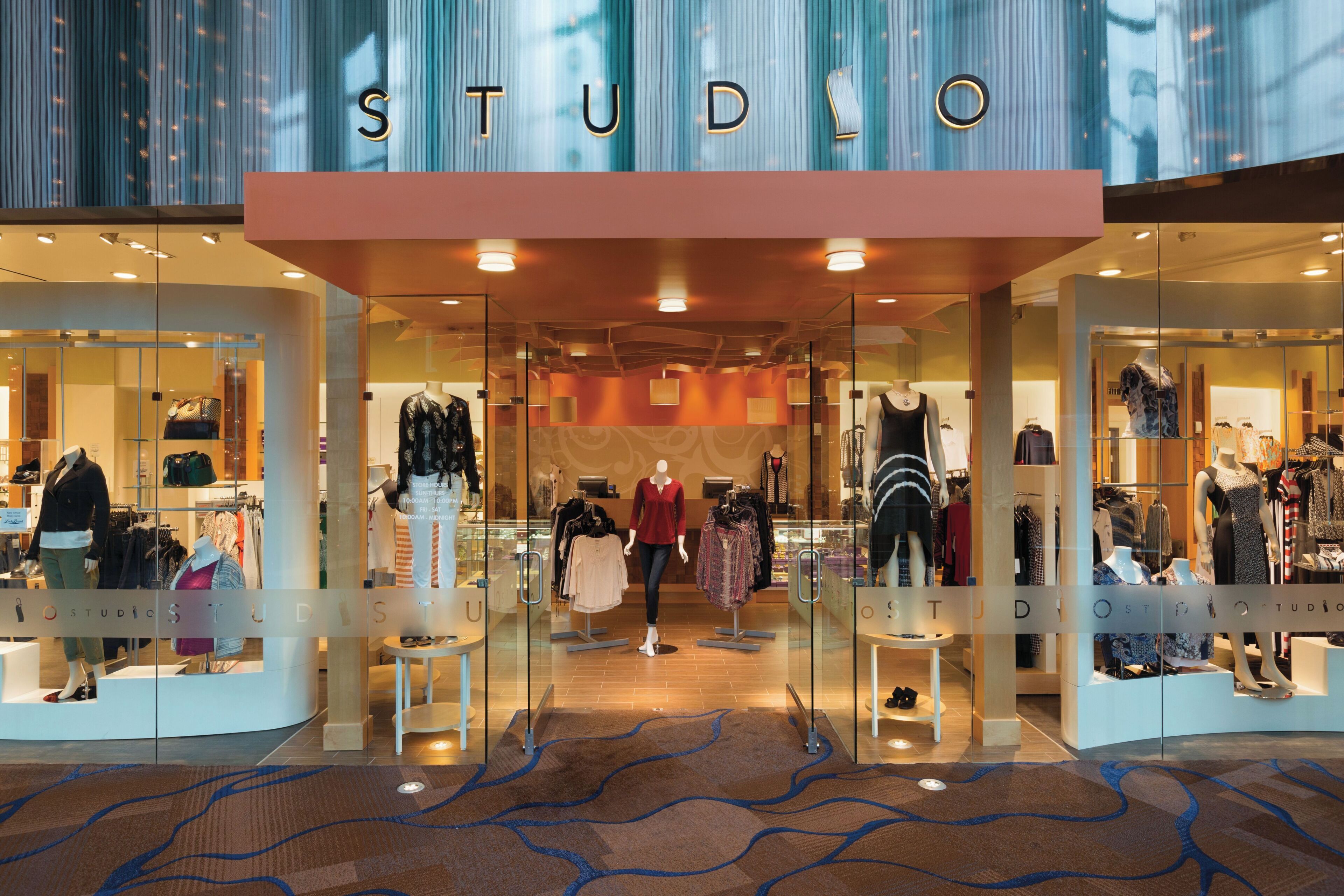 A storefront with the word 'STUDIO' above the entrance, displaying various clothing items and accessories.
