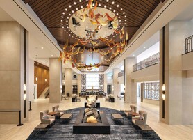 A spacious lobby with a central seating area, a decorative ceiling feature, and a staircase leading to an upper level.