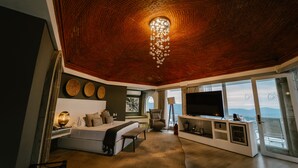 A modern hotel room with a curved ceiling, a large bed, a TV, and a balcony with a view. - Hotel Boutique de Cantera y Plata (Taxco)