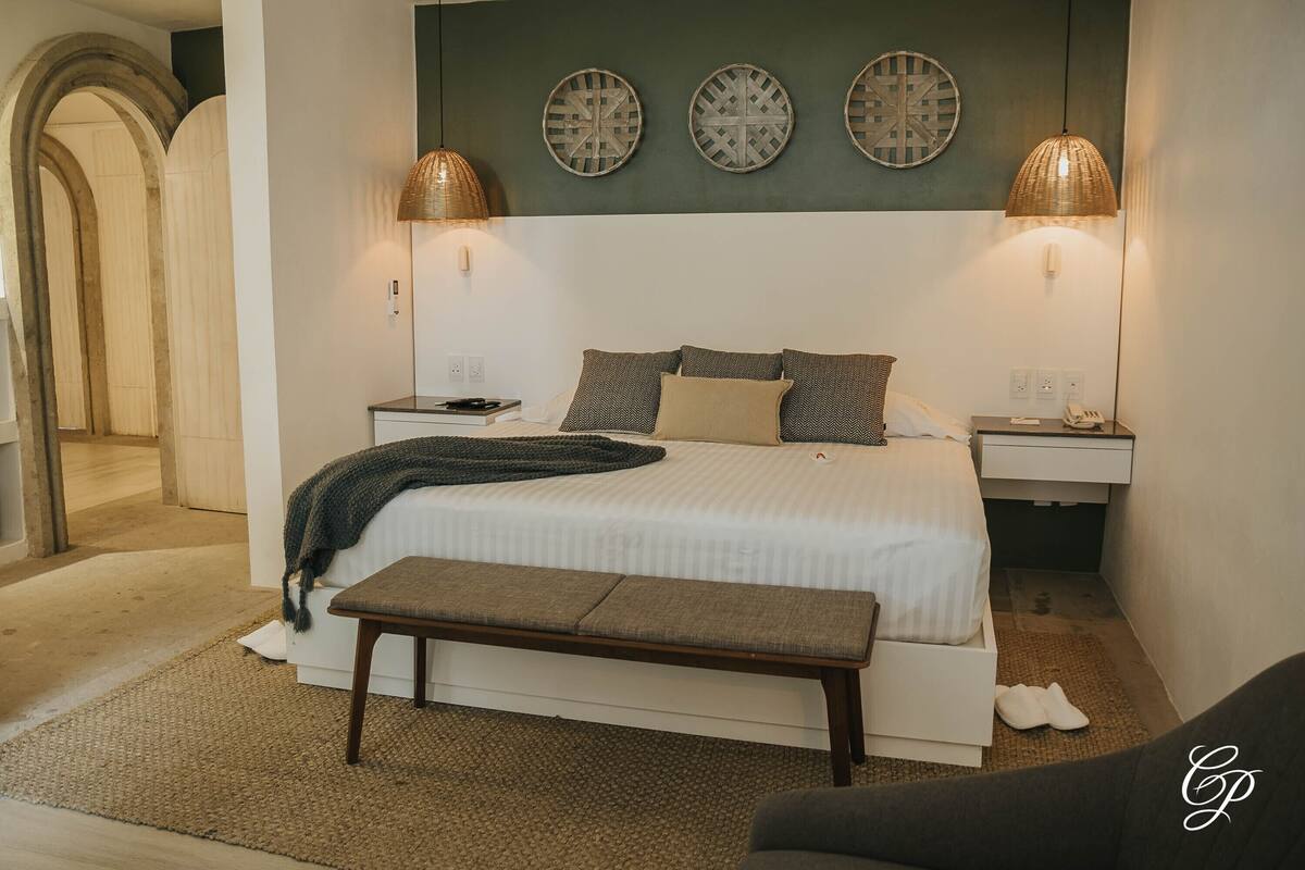 Ein Schlafzimmer mit Bett, Nachttischen, einer Bank und dekorativer Wandgestaltung.