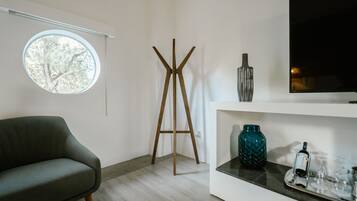 Una sala de estar moderna con un sofá, una lámpara de pie, un televisor y una estantería con adornos.