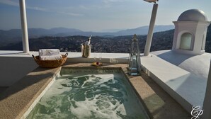 A rooftop terrace with a hot tub, a wicker basket, a glass of wine, and a view of the city and mountains. - Hotel Boutique de Cantera y Plata (Taxco)