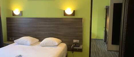 Habitación de hotel con una cama grande, dos lámparas de noche, una mesita de noche y un cuadro colgado en la pared.