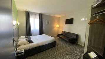 A hotel room with a bed, a sofa, a TV, a lamp, and a wardrobe.