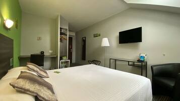 Una habitación de hotel con una cama grande, un escritorio, una silla, un televisor y un armario.
