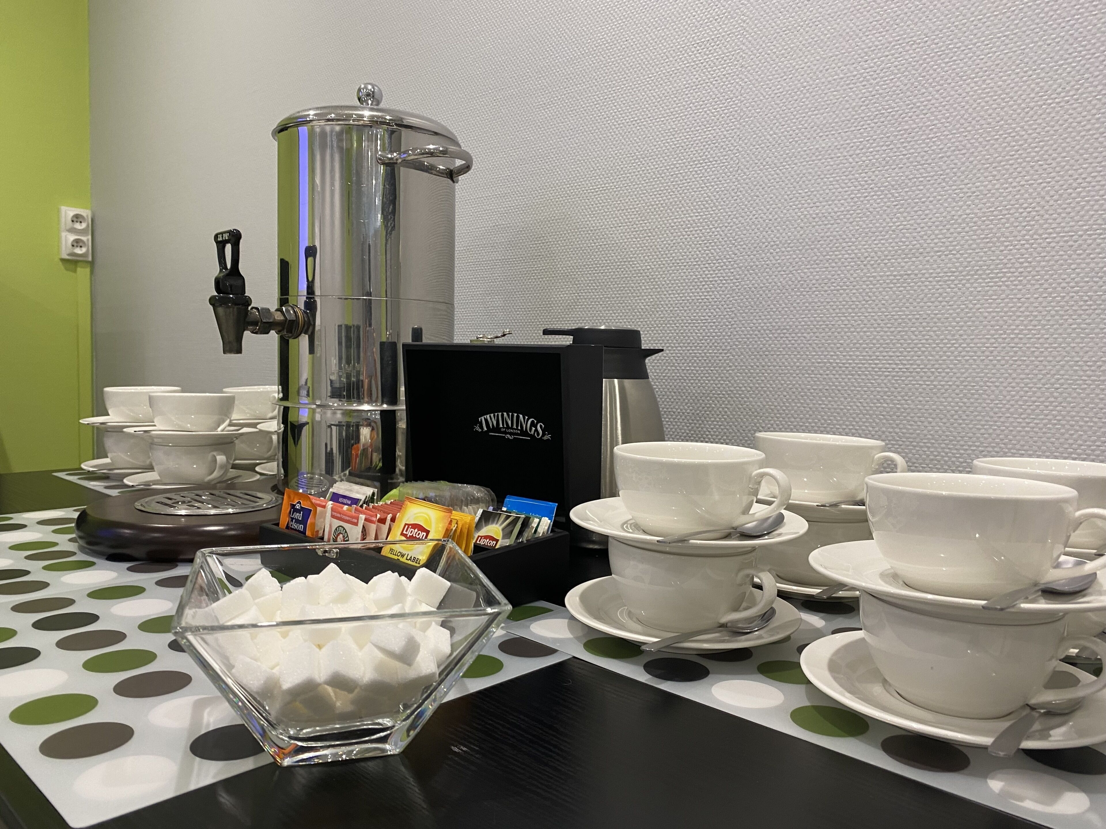 A coffee station with a coffee maker, cups, and sugar cubes.