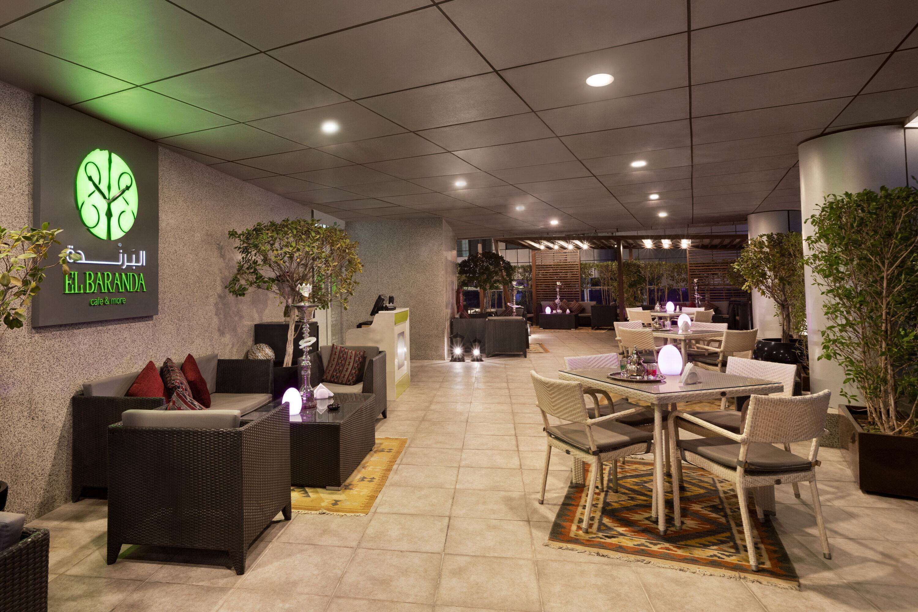 Ein moderner Lounge-Bereich mit Korbmöbeln, einer Rezeption und Topfpflanzen.