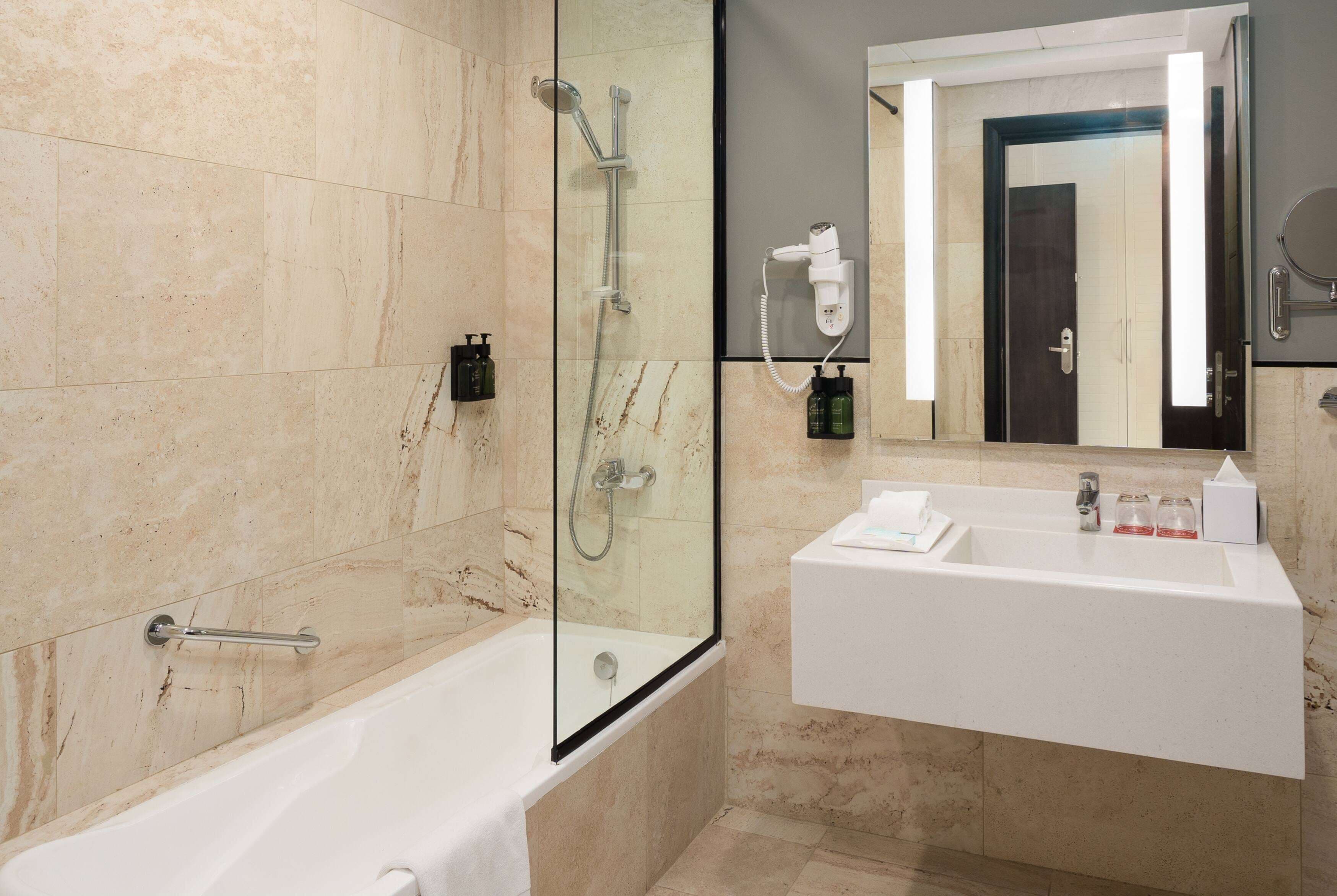 Un baño moderno con ducha de vidrio, una bañera blanca y un tocador con espejo.