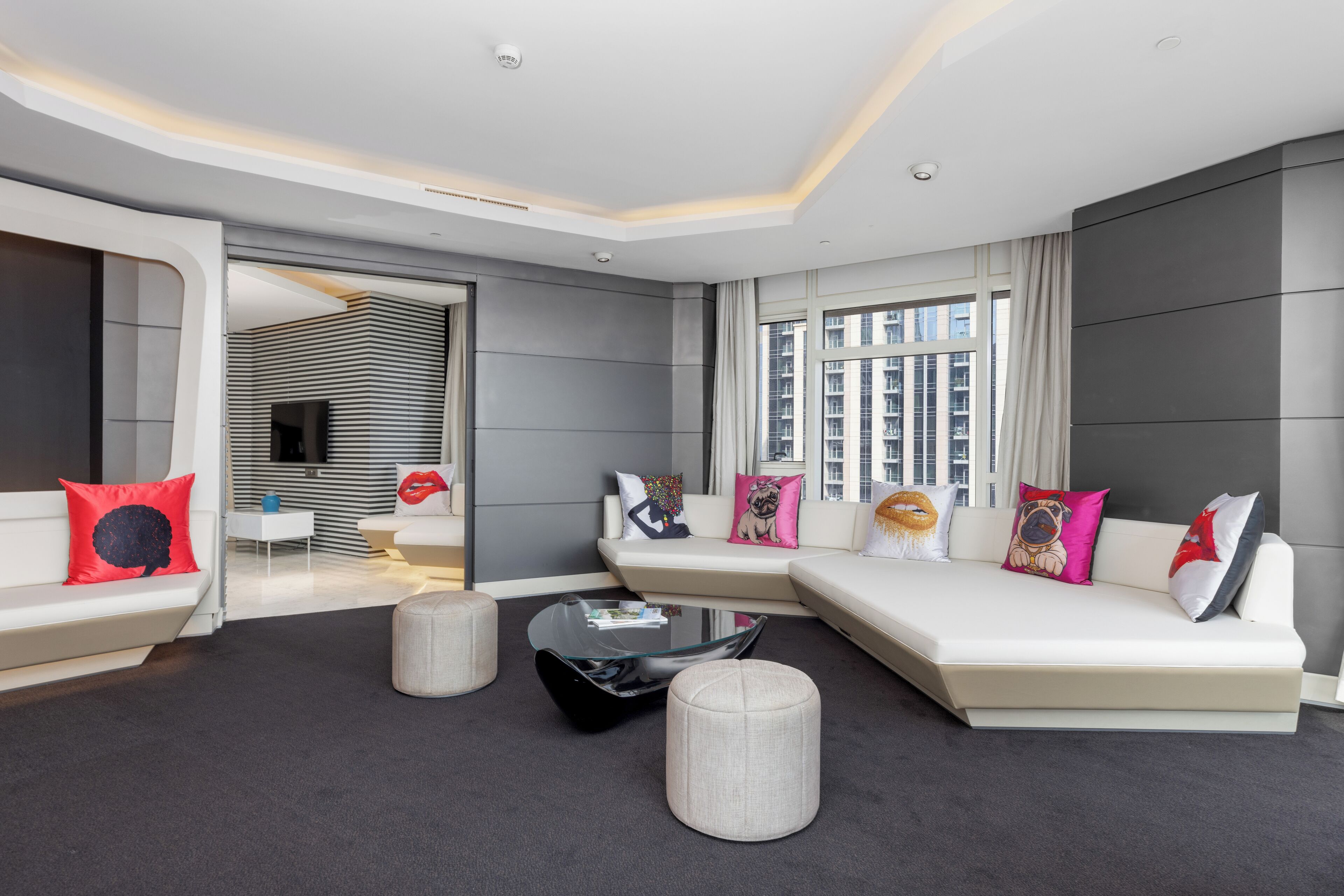 A modern living room with a sectional sofa, a glass coffee table, and a view of the city through large windows.