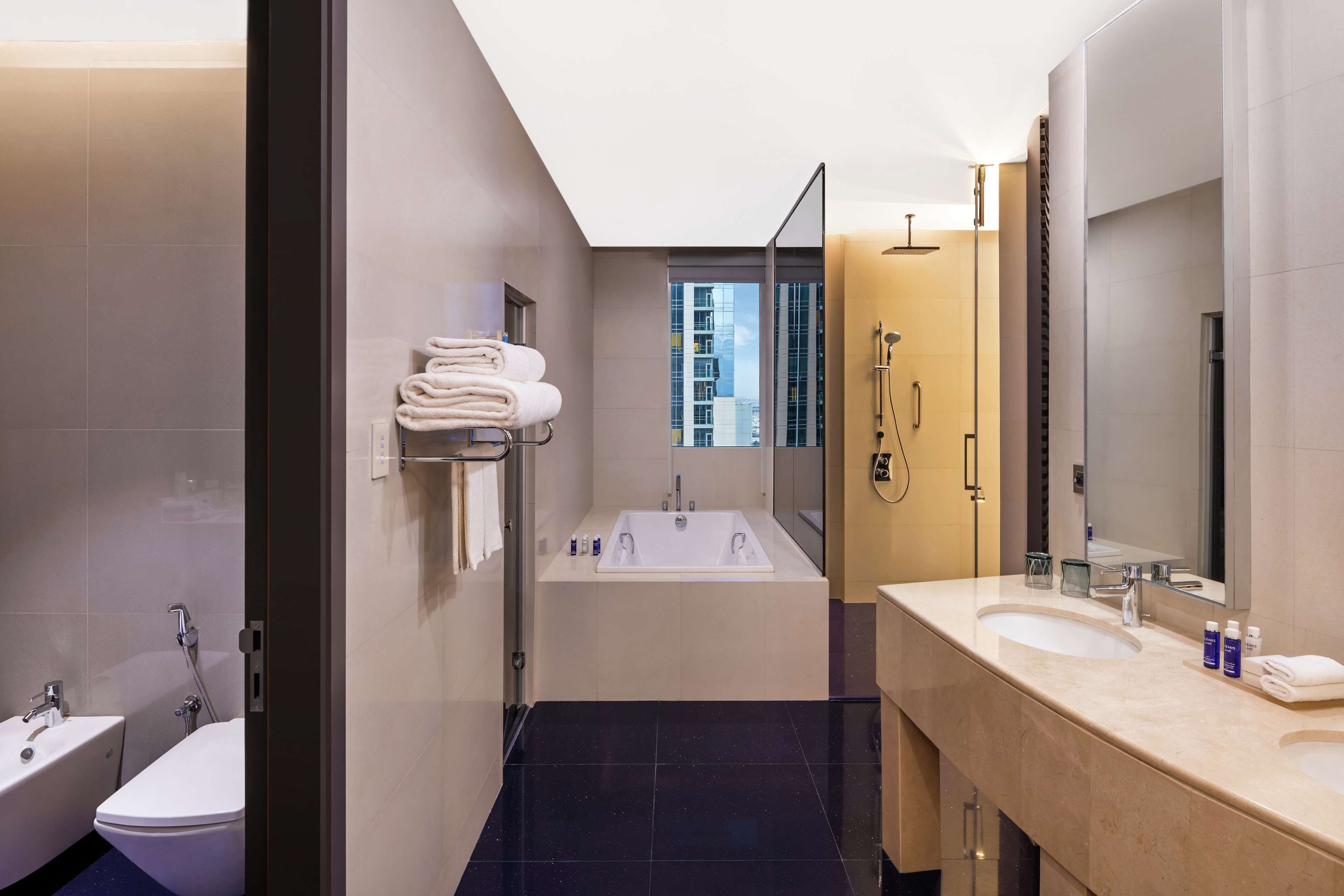 Un baño moderno con una bañera, un espejo grande y un lavabo.