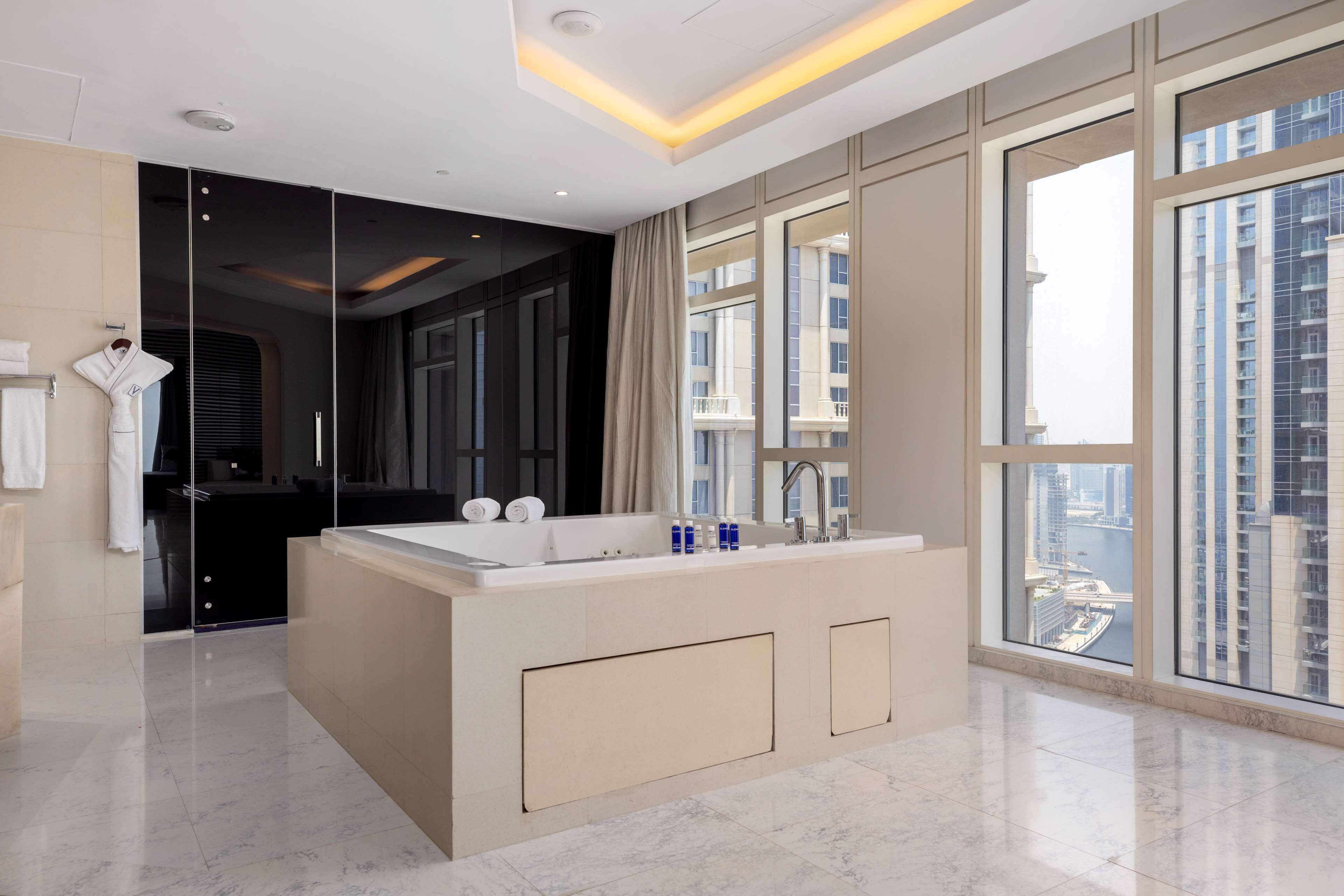 A modern bathroom with a large mirror, a bathtub, and a vanity with a sink.
