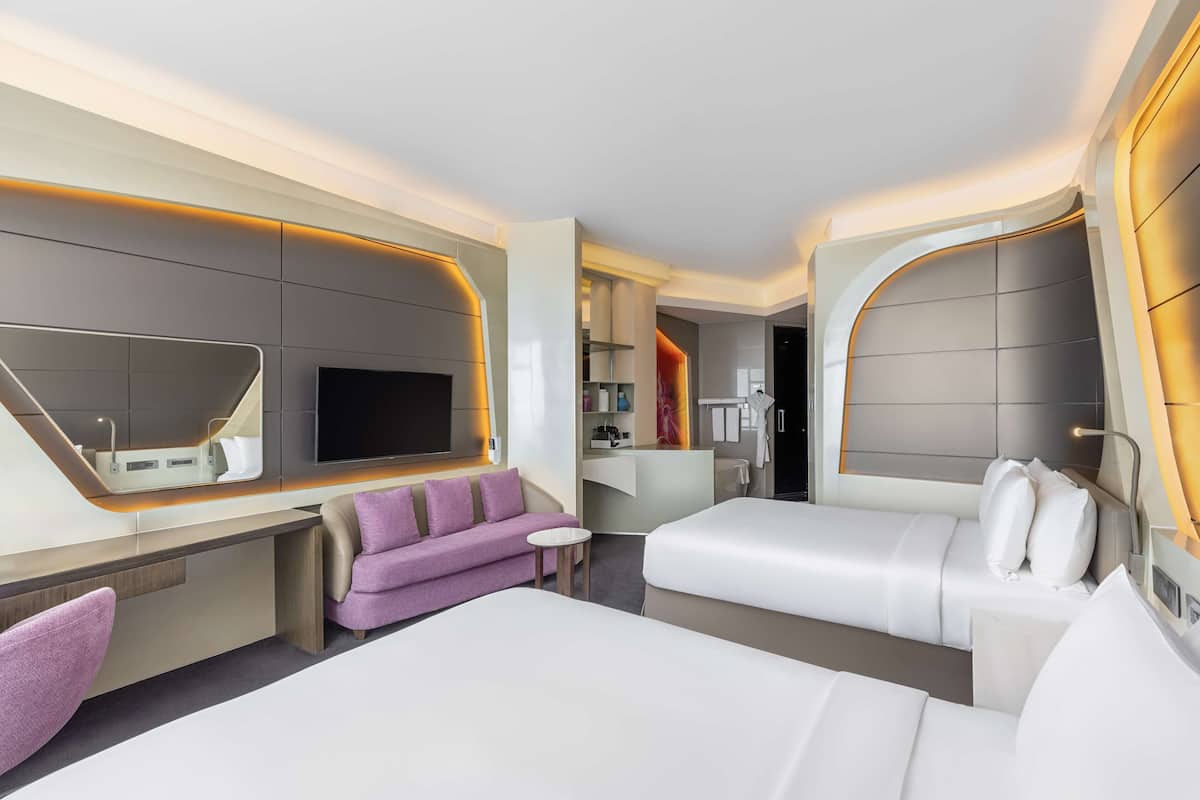 Una camera d'albergo moderna con un letto grande, una poltrona, una scrivania e una televisione.