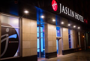 The exterior of Jaslin Hotel with a prominent sign, large windows, and a modern facade. - Jaslin Hotel (Chicago)