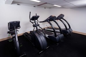 A fitness room with three treadmills, one elliptical, and a stationary bike. - Jaslin Hotel (Chicago)