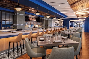 A modern restaurant with a bar area, multiple tables, and chairs. - Harrah's Cherokee Valley River – A Caesars Rewards Destination (Murphy)