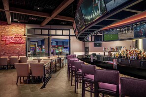 A bar area with a neon sign, seating, a counter with bottles, and a sports screen. - Harrah's Cherokee Valley River – A Caesars Rewards Destination (Murphy)