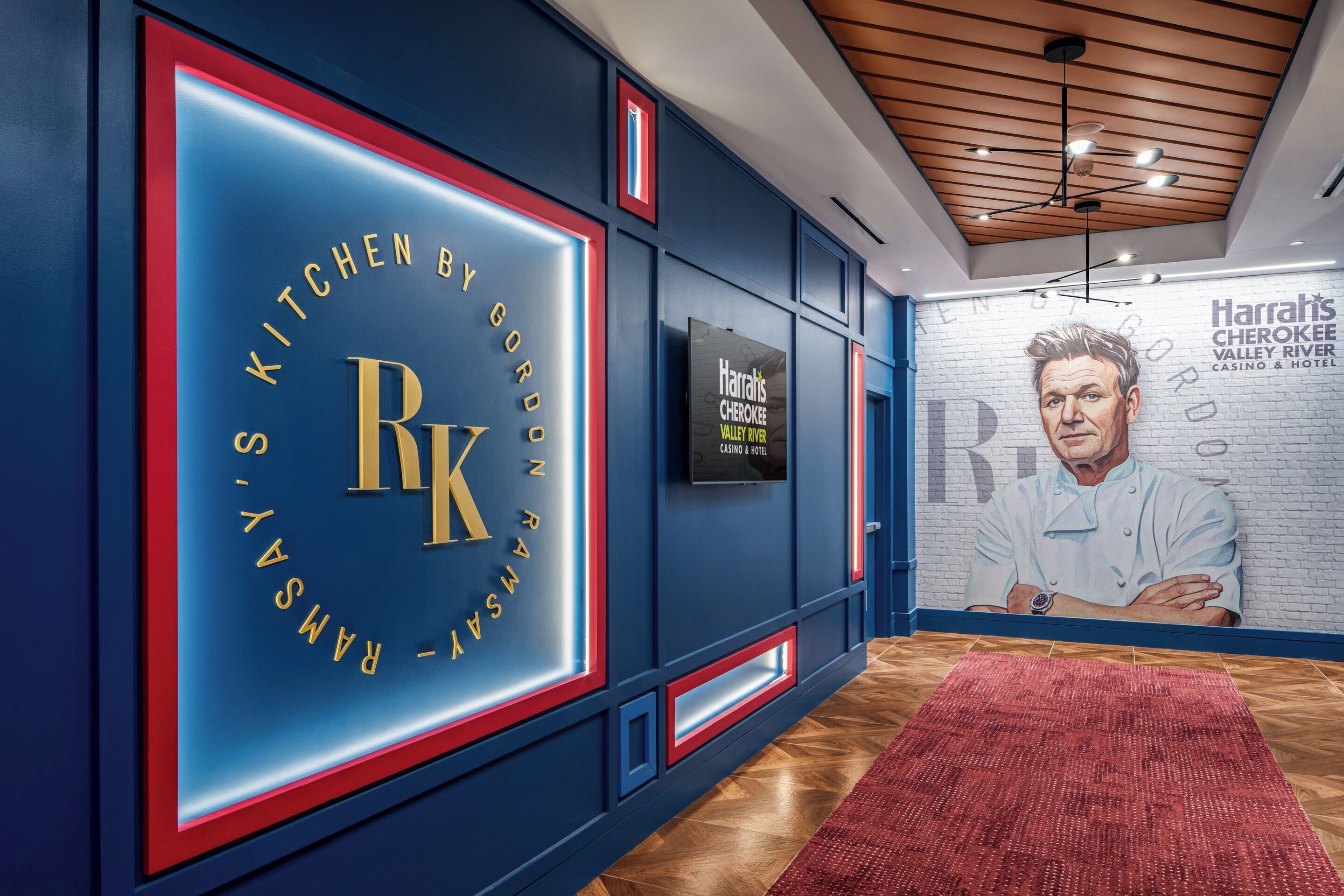 Ein modernes Interieur mit einem gut sichtbaren RK-Zeichen, einem Wandgemälde des Harrah's Cherokee Valley River Casino & Hotel und einem roten Teppich, der zu einer Tür führt.