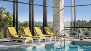A pool area with lounge chairs, a marble column, and a view of trees and mountains. - Harrah's Cherokee Valley River Hotel & Casino – A Caesars Rewards Destination (Murphy)