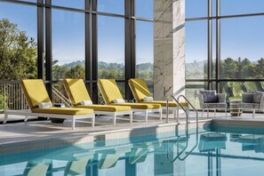 Un espace piscine avec des chaises longues, une colonne de marbre et une vue sur les arbres et les montagnes.