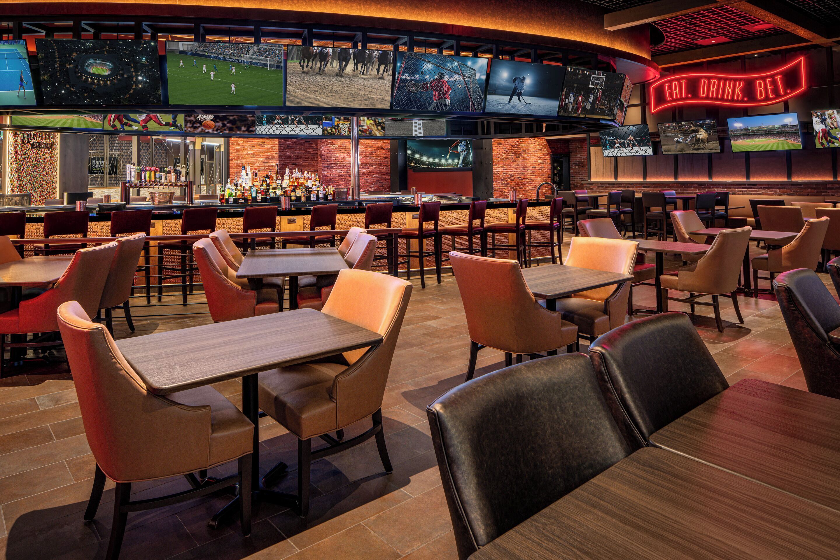 A sports bar with multiple screens, bar area, and seating for patrons.