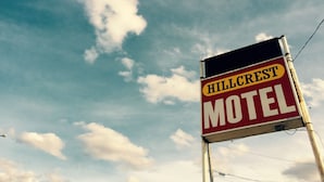 Señal del motel Hillcrest contra un cielo con nubes.