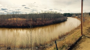 Un río serpenteando por una zona boscosa con un sendero de tierra a su lado.