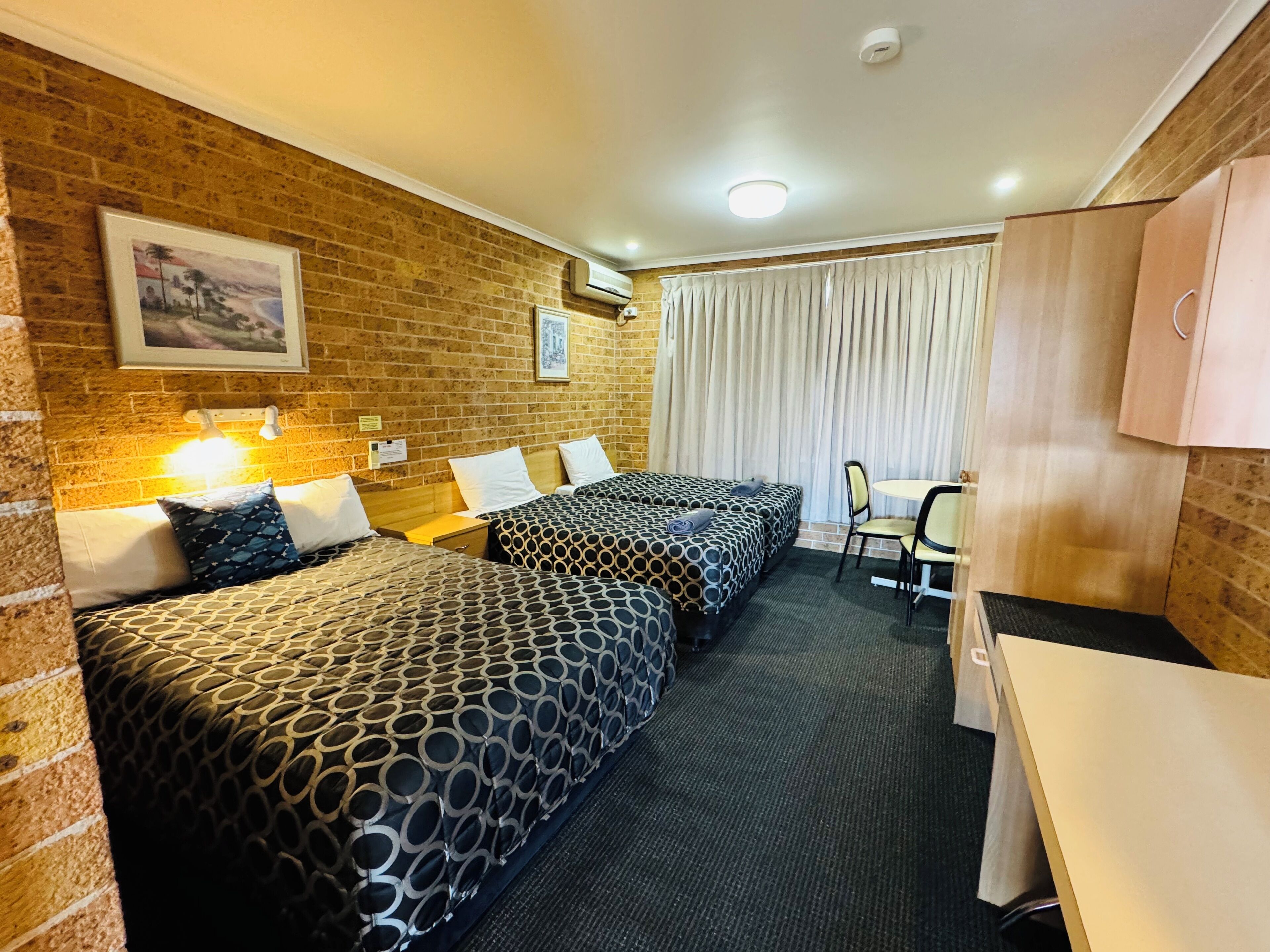 A hotel room with two beds, a desk, and a chair.