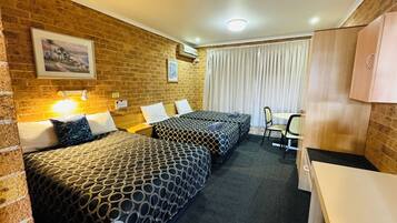A hotel room with two beds, a desk, and a chair.