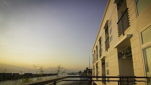 A modern building with multiple balconies and large windows, overlooking a body of water with a distant mountain range. - The Reef Hotel and Residences (Olongapo)