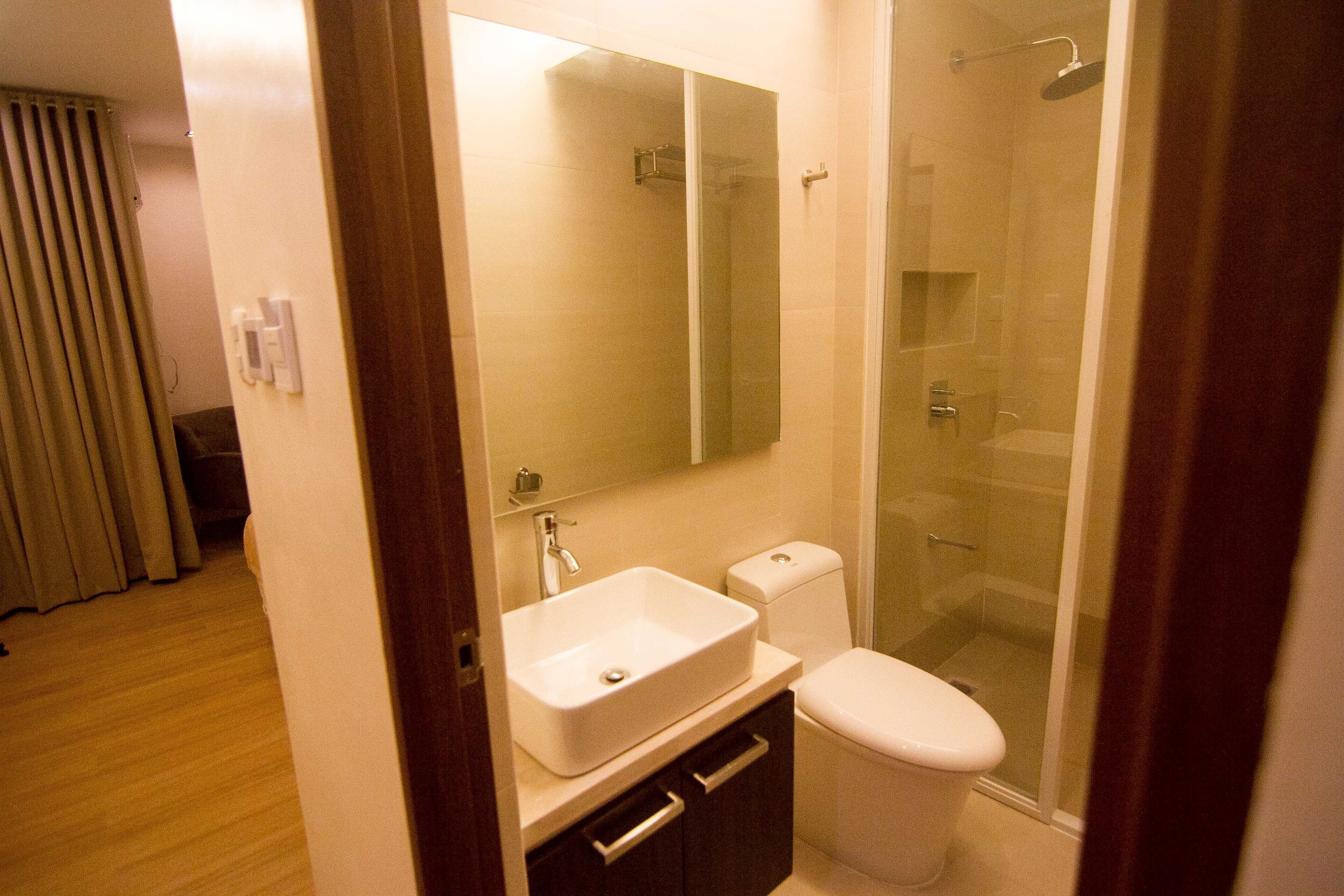 A bathroom with a sink, mirror, toilet, and glass-enclosed shower.