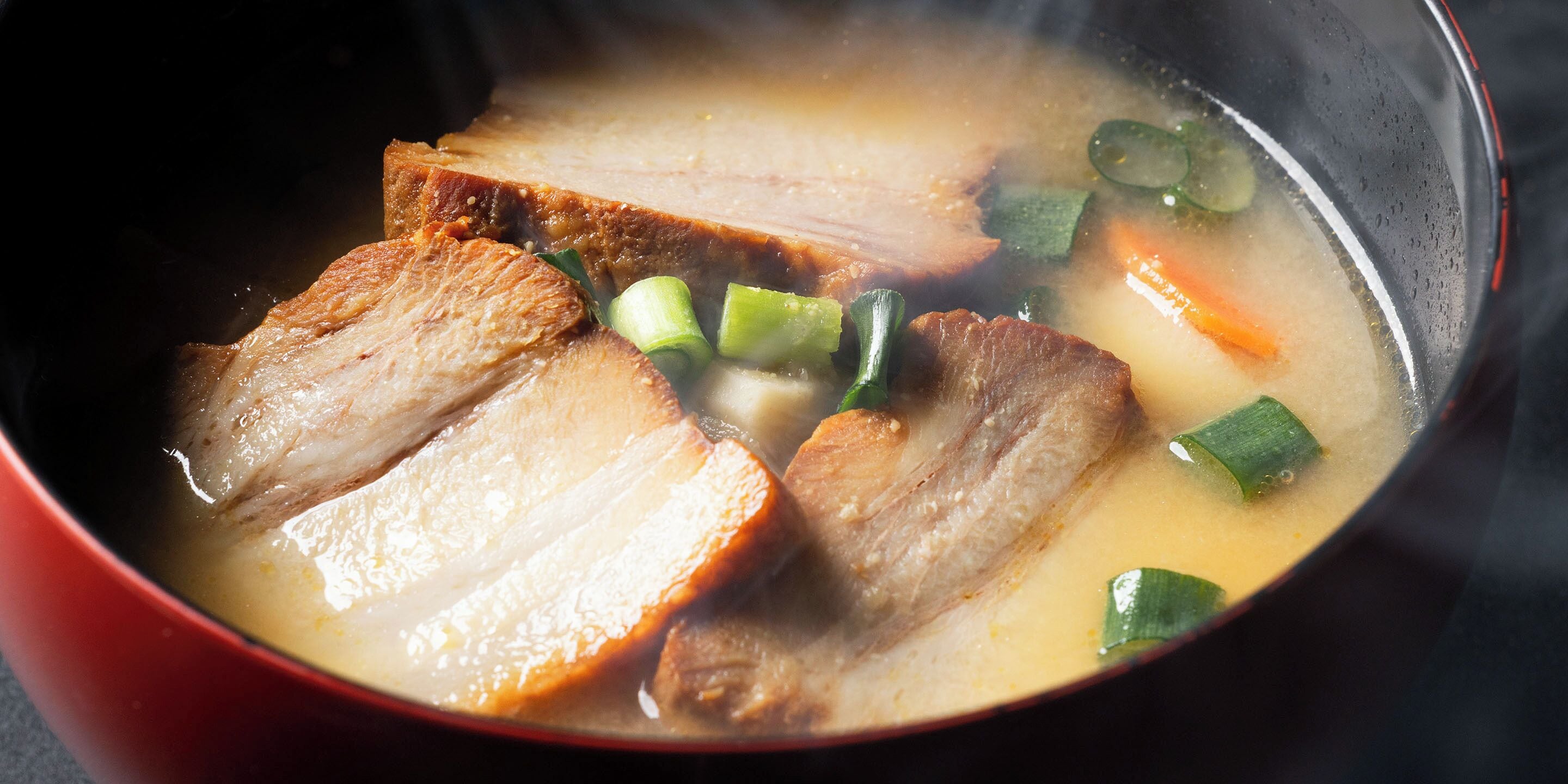 Uma tigela de sopa com fatias de carne e legumes.