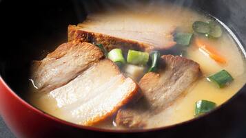 Uma tigela de sopa com fatias de carne e legumes.