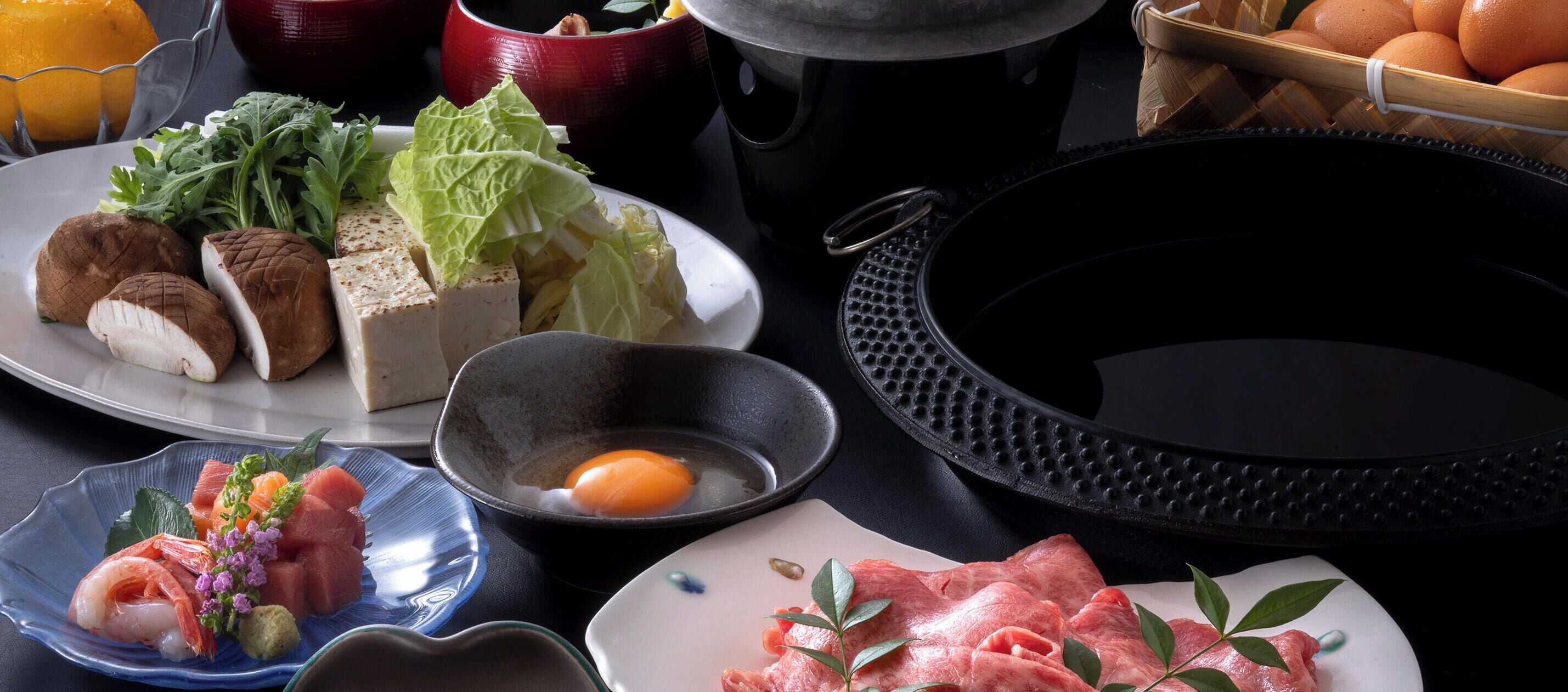 Variedad de alimentos, como sashimi, tofu y verduras, sobre una mesa.