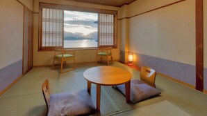 A tatami mat room with a low table, two chairs, a window with shoji screens, and a floor lamp. - Fujikawaguchiko Onsen Hotel Asafuji (Fujikawaguchiko)