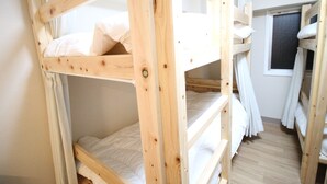 A bunk bed room with white bedding and curtains, wooden headboard, and a window with curtains. - Glocal Nagoya Backpackers Hostel (Nagoya)