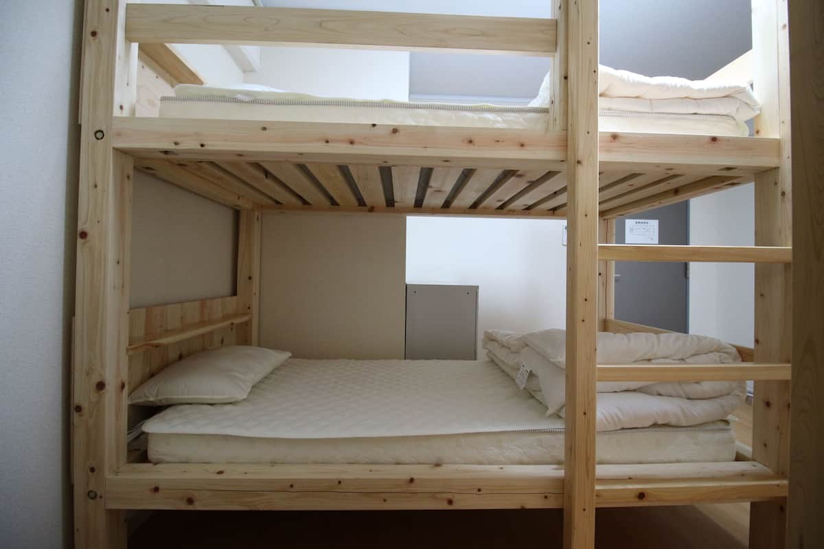 Una litera con tragaluz, un escritorio y un mueble pequeño.