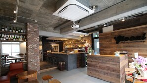 A modern bar with a wooden counter, brick walls, and a variety of bottles on shelves. - Glocal Nagoya Backpackers Hostel (Nagoya)